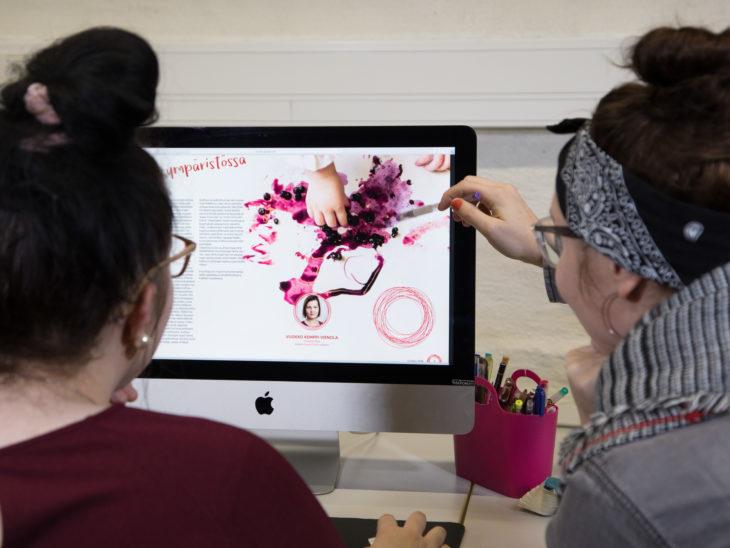 Kaksi opiskelijaa tarkastelee graafisen alan julkaisuvedosta tietokoneen näytöltä.