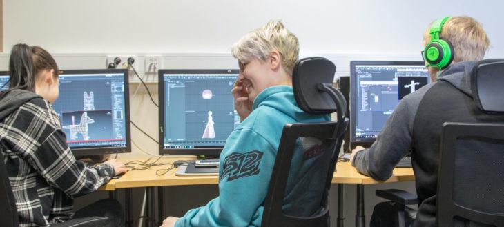 Kuvassa kolme opiskelijaa piirtää pelihahmoja tietokoneilla. 