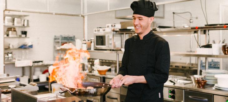 Kuvassa opiskelija liekittää pihviä opetusravintolan keittiössä.
