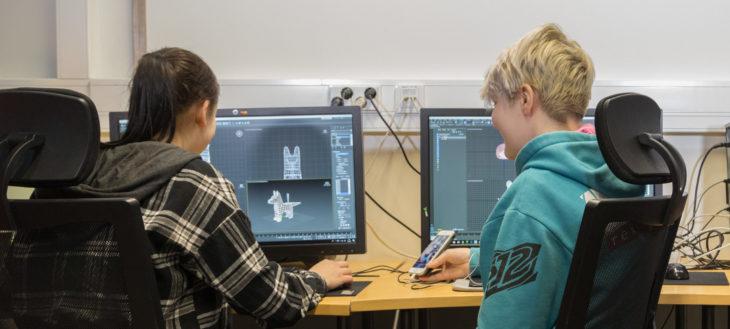 Kuvassa kaksi opiskelijaa piirtää pelihahmoja tietokoneella.