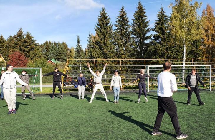Opiskelijat lämmittelevät lihaksiaan hyppyharjoituksilla jalkapallokentällä.