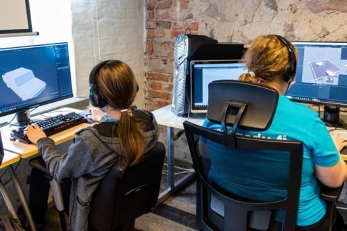 Kaksi opiskelijaa suunnittelee pelejä tietokoneillaan.
