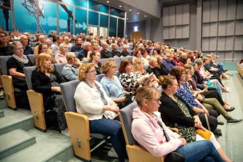 osa sataedulaista yleisöä istumassa auditoriossa