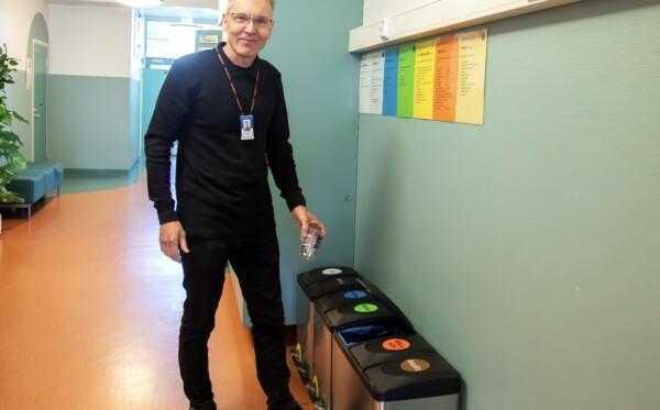Tapio Hemiä esittelee käytävällä olevaa kierrätyspistettä