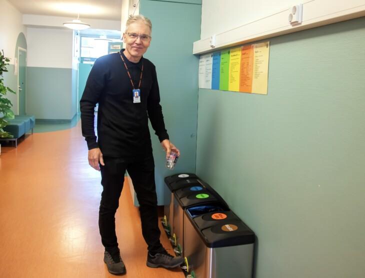 Tapio Hemiä esittelee käytävällä olevaa kierrätyspistettä
