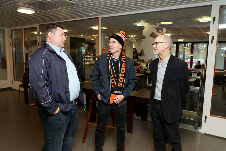 Sähköalan opettaja Petri Tyrköllä (vas.), Tapio Hemiällä ja jo eläköityneellä rehtori Hannu Mansikkakorvella on takanaan iso määrä yhteisiä työvuosia. Miehet jutteleva kahvion edessä.